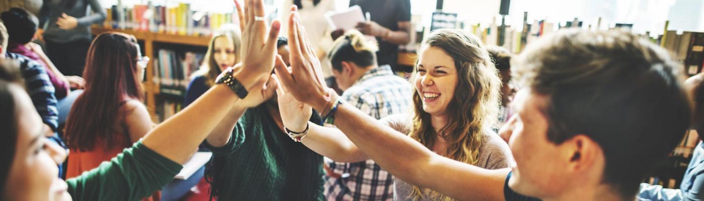 A group of students high-fiving and smiling at each other.
