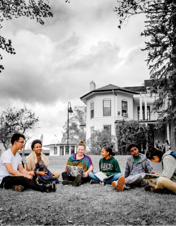 Students sitting and talking on a grass feild.
