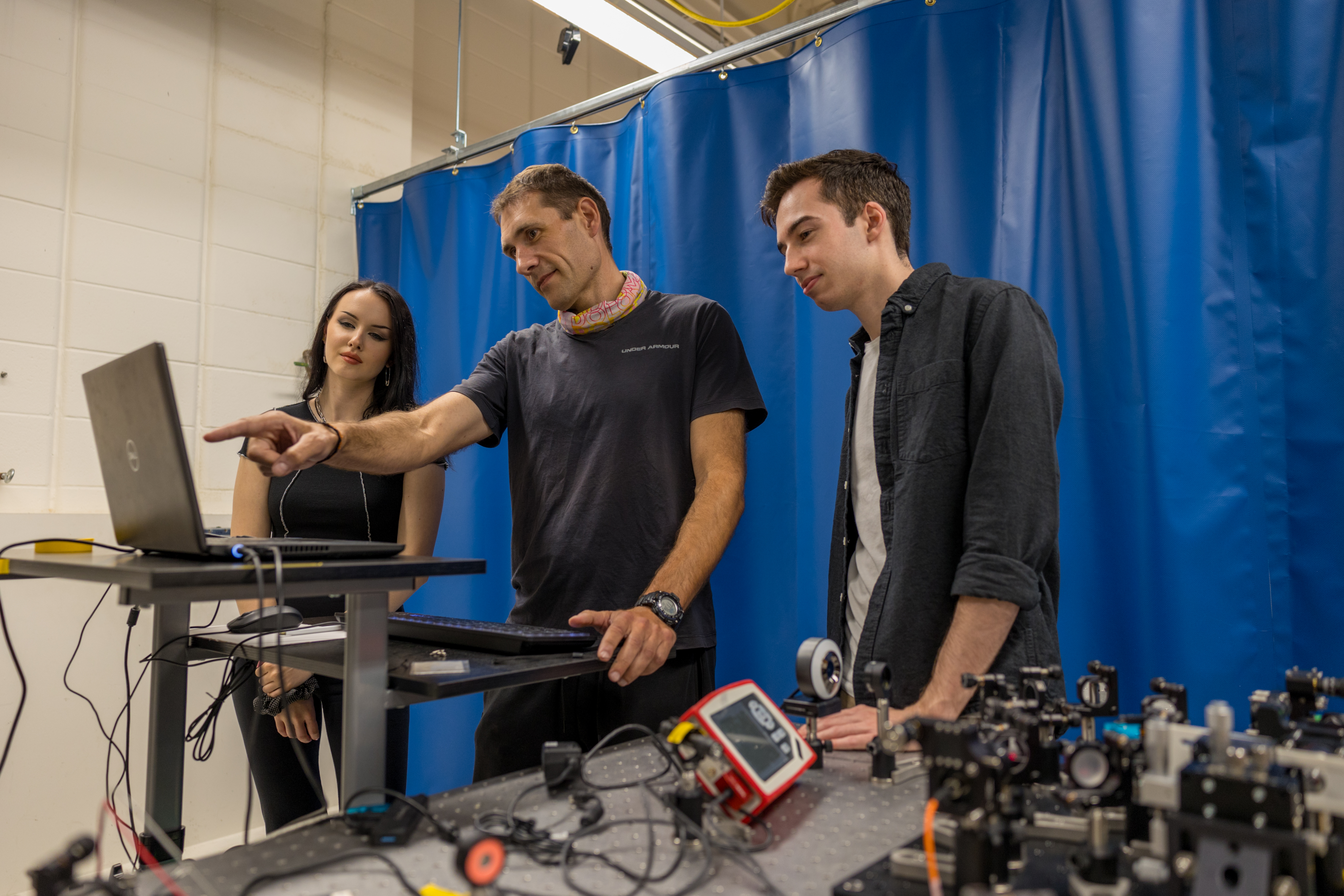 Students and professor looking at a laptop screen