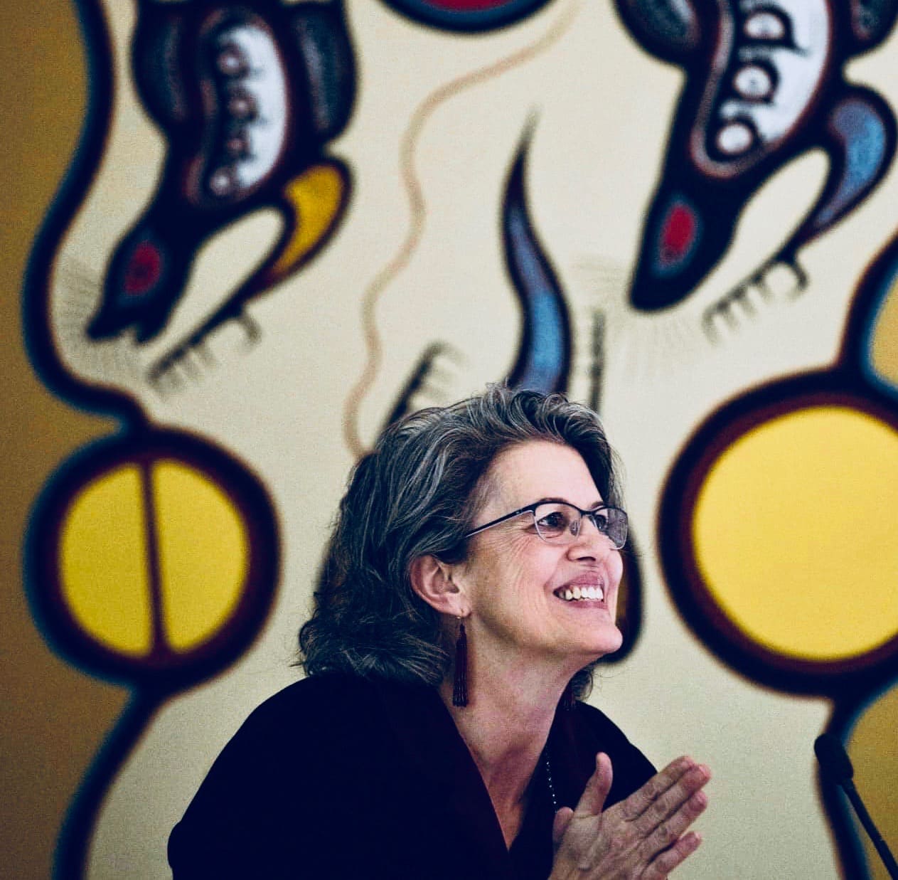 Side profile of Barbara Wall, smiling, in front of large painting