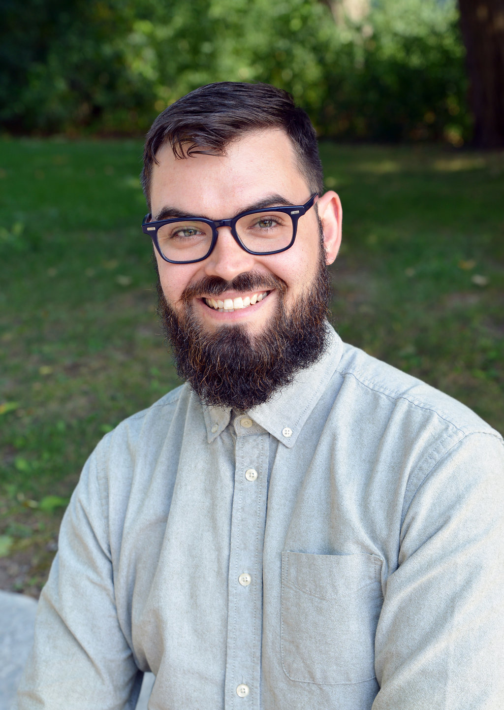 Brent Bellamy smiling, grass and trees in the background