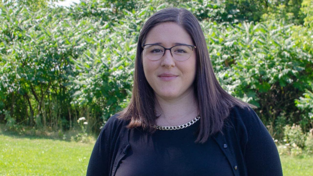 Shannon standing outside in front of sumac trees
