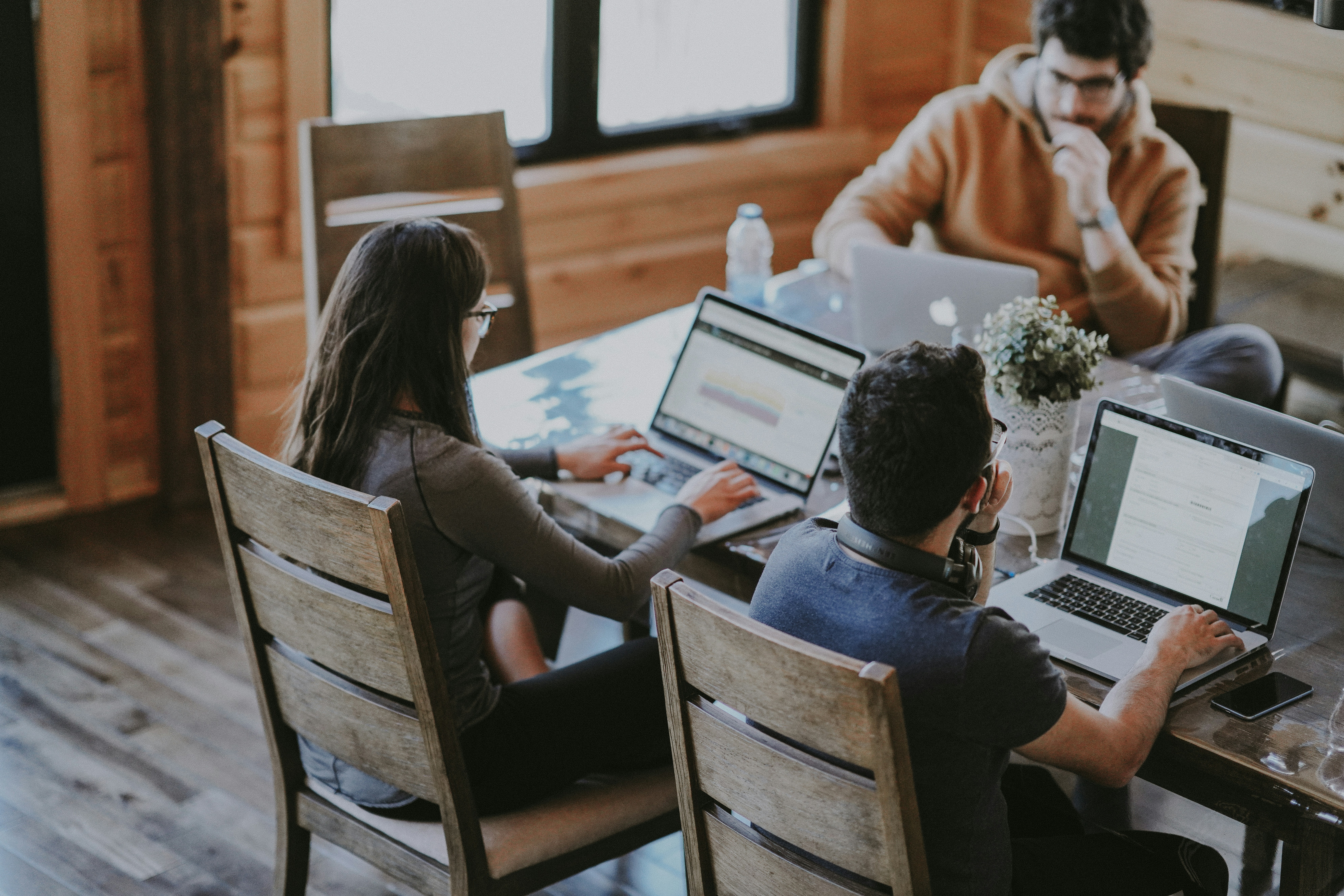 three people sitting at a table working on their laptops