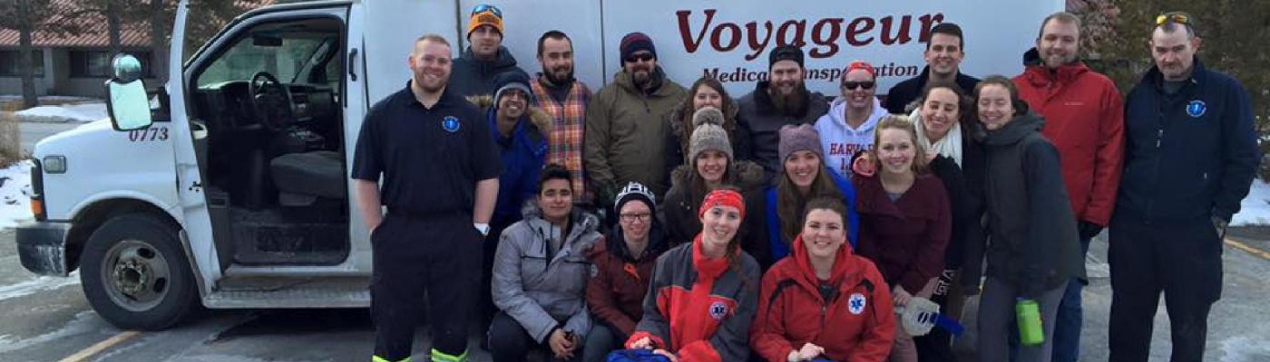 Team standing/crouching with ambulance and paramedics