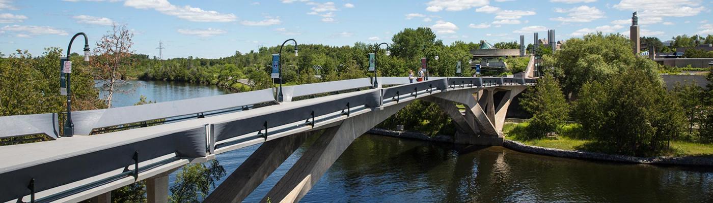 Summertime exterior view of the Faryon bridge with people waking across