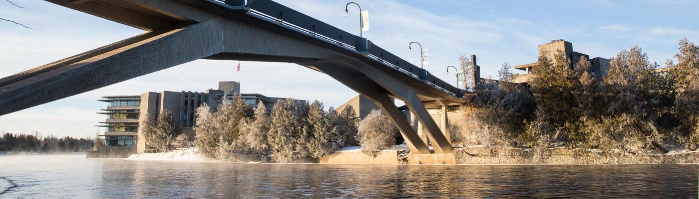 Exterior winter view of the Bata Library taken from the east bank of the Otonabee River looking underneath the Faryon Bridge in the morning light