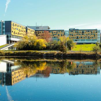 Exterior view of Gzowski College in the afternoon fall sun from across the Otonabee river