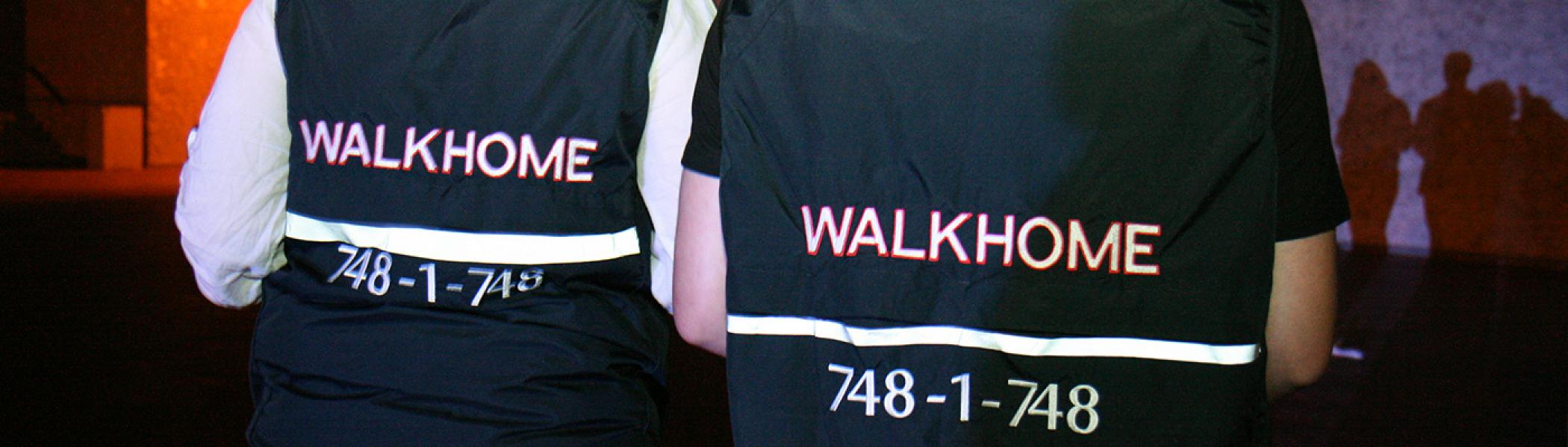 2 people wearing a vest that says "WALKHOME" at the back