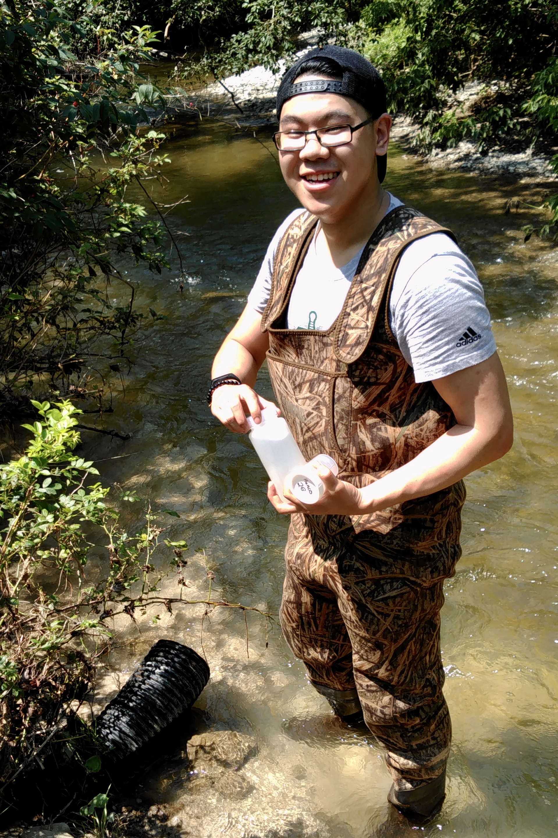 smiling student in hipwaders standing in water