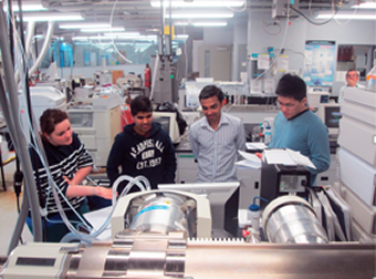 Four researchers gathering around a monitor for an instrument at Trent's Water Quality Centre.