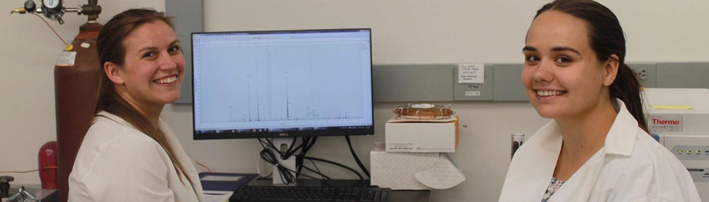 Two scientists analyzing data shown on a monitor.
